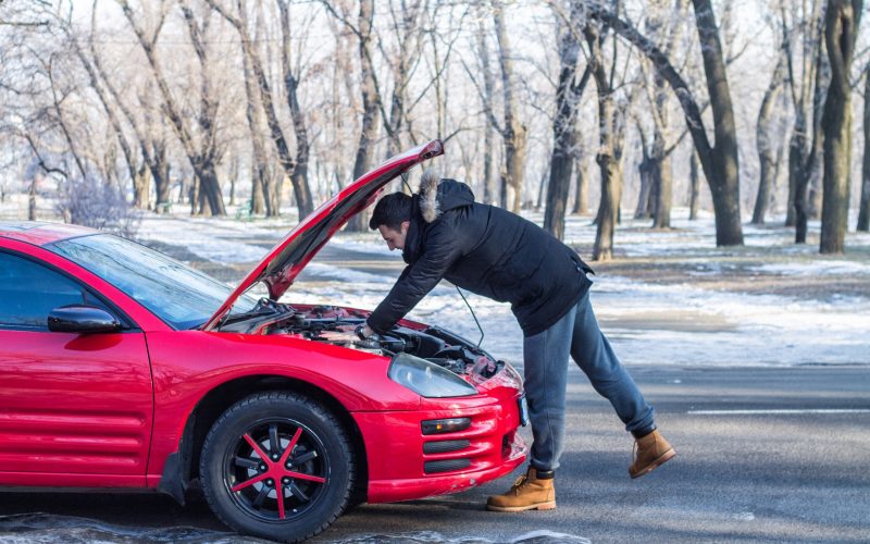 Man in trouble with his broken car .He is worried, he is looking at engine under hood.