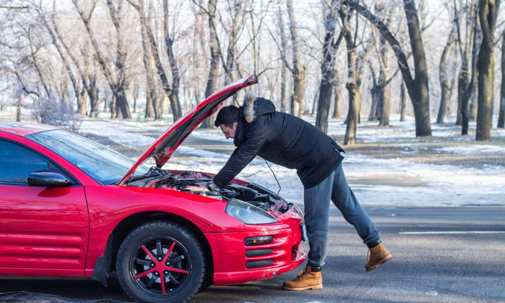 Man in trouble with his broken car .He is worried, he is looking at engine under hood.
