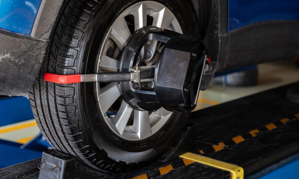 Wheel alignment equipment grip the tire of car wheel in car repair shop. Auto wheel alignment in workshop of service station. Car wheel balance. Suspension adjustment. Vehicle inside garage workshop.
